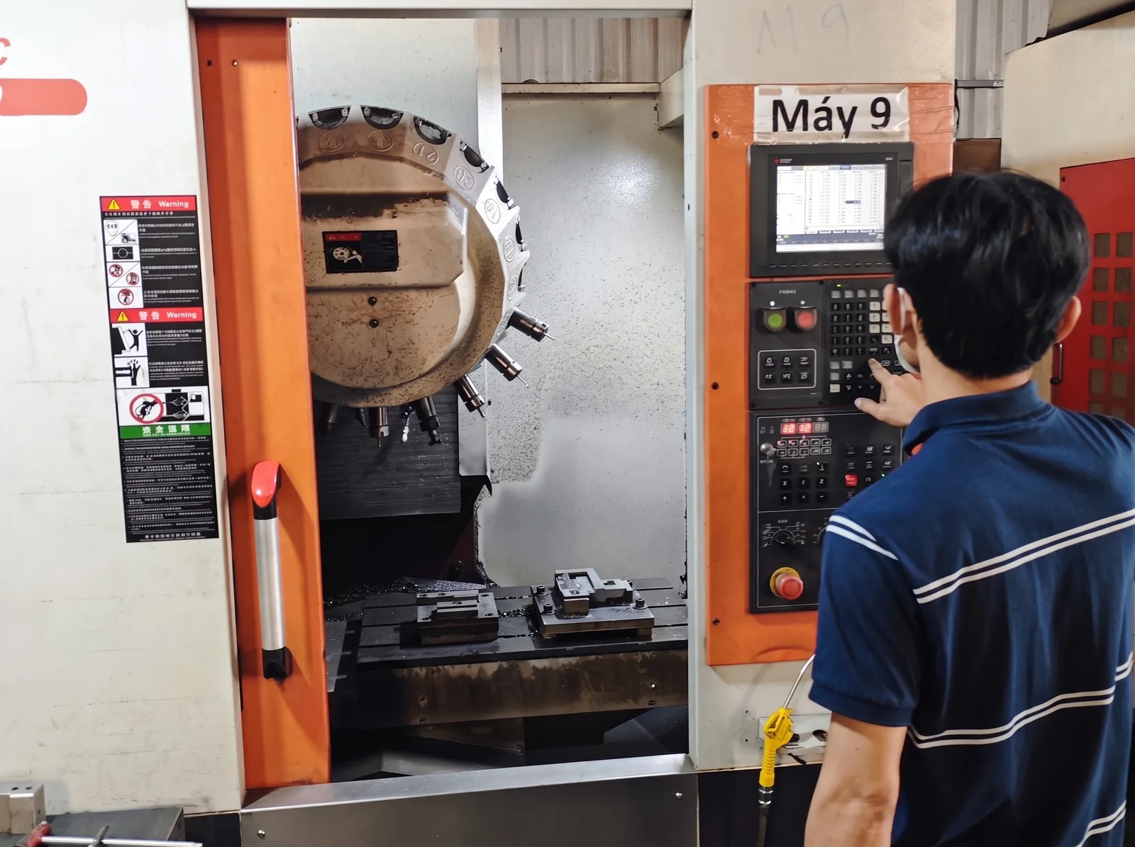 An operator at the control of a vertical machining center